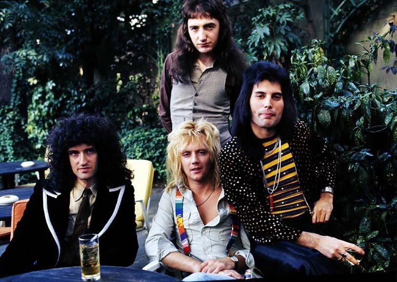 Queen leta 1975. Od leve - Brian May (kitara in vokal), stoji baisist in pevec John Deacon, Roger Taylor (bobni in vokal) in Freddie.